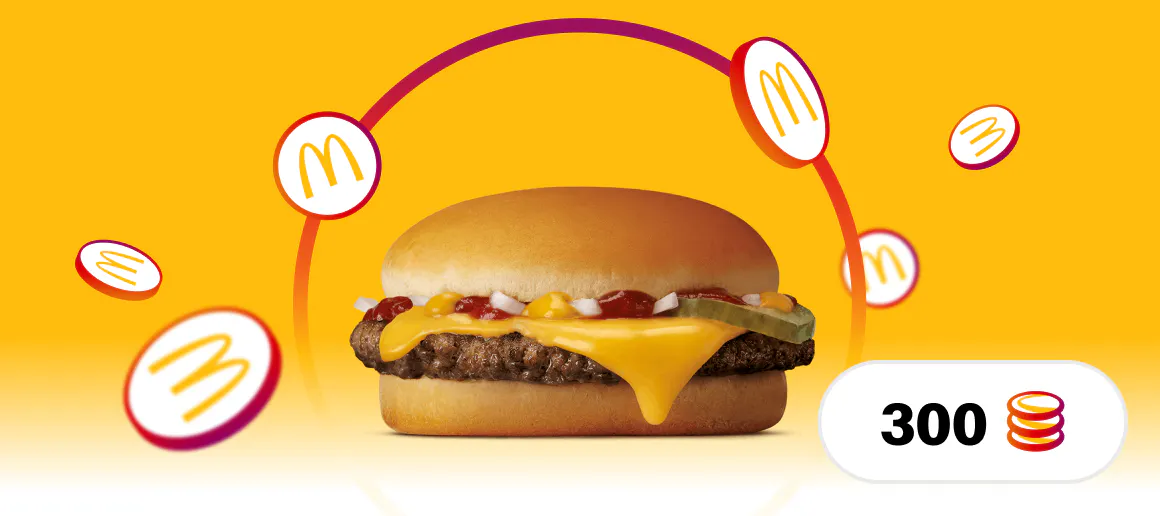 Imatge d'una hamburguesa amb formatge de McDonalds col·locada sobre un fons groc amb monedes amb el logotip de MyMcDonalds al voltant i una icona a la part inferior dreta amb el número 300 i una icona de moneda
